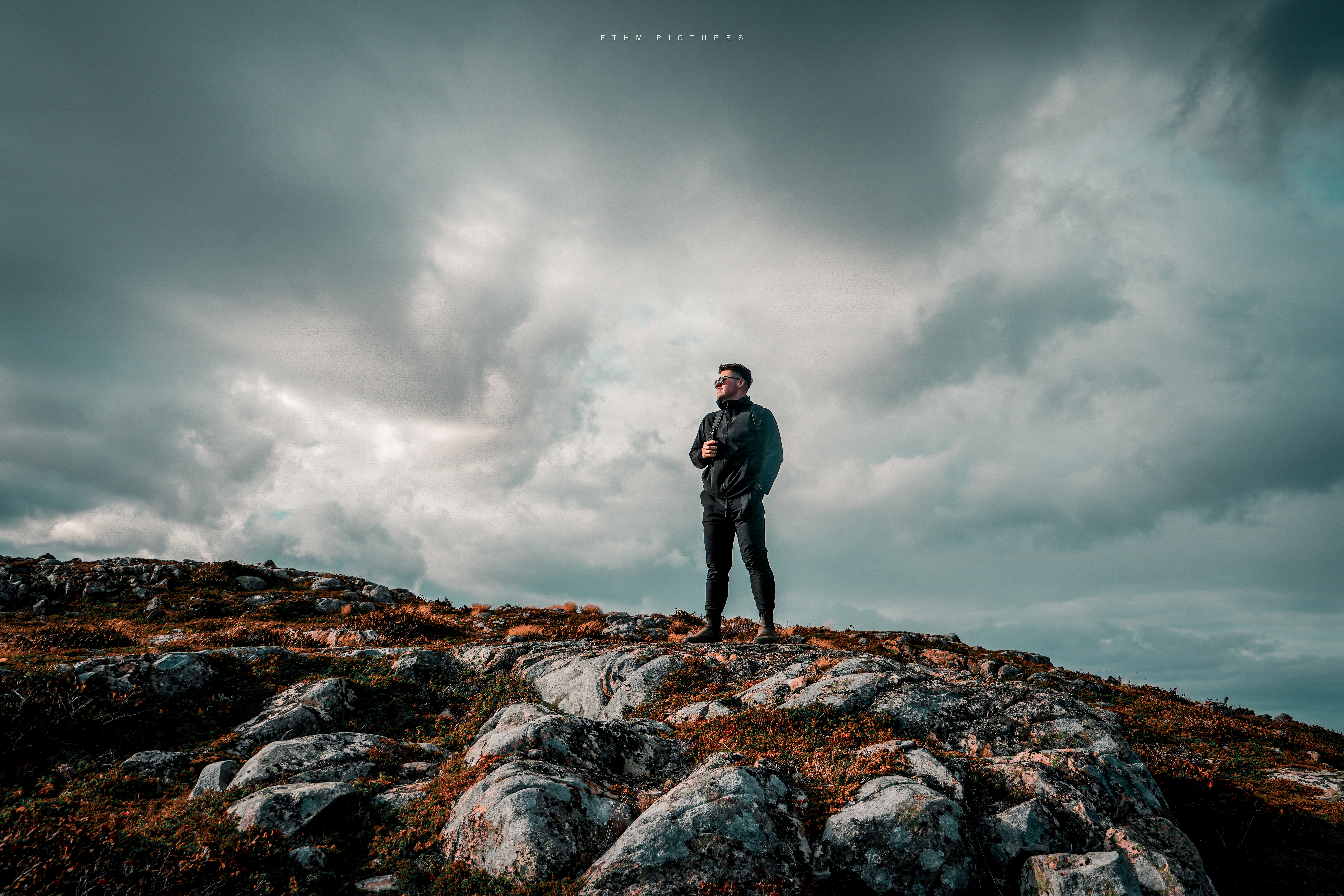 Figure standing on rocky barrens under a dramatic sky