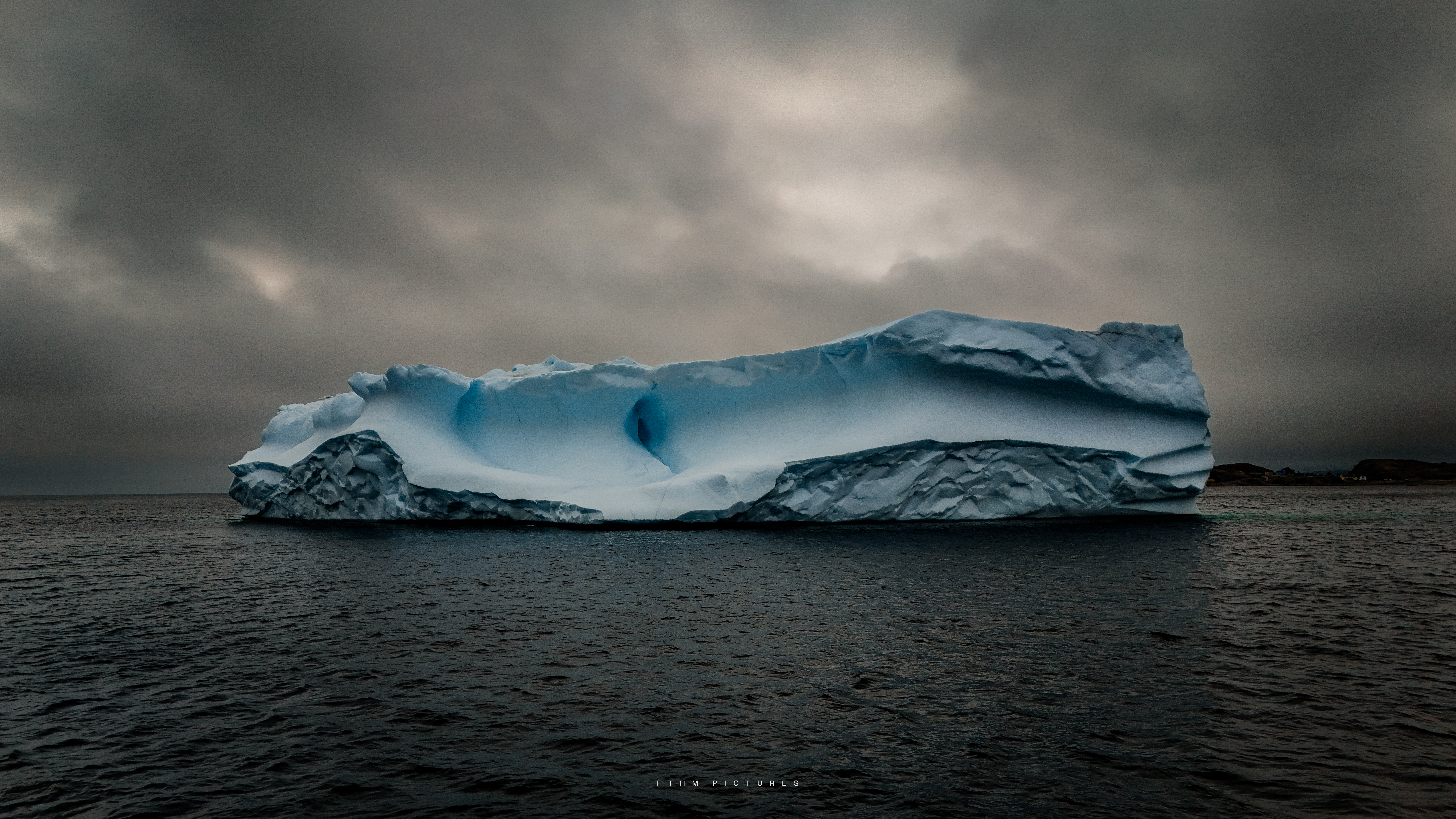 Moody iceberg on grey water under stormy skies